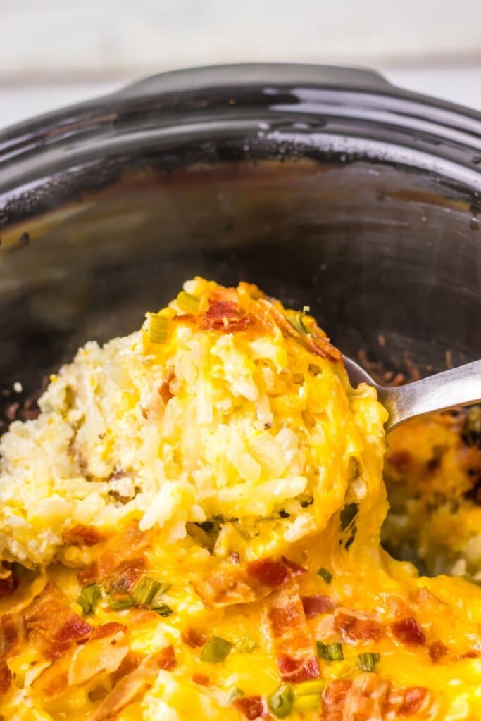 Spoonful of potatoes being removed from a crockpot.