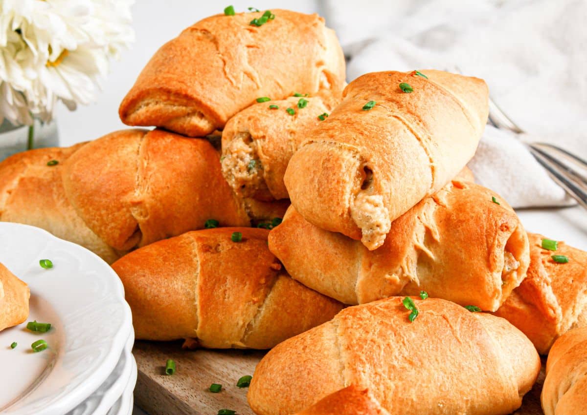 Sausage crescent rolls stacked on a plate.