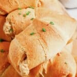 Sausage crescent rolls stacked on a plate.