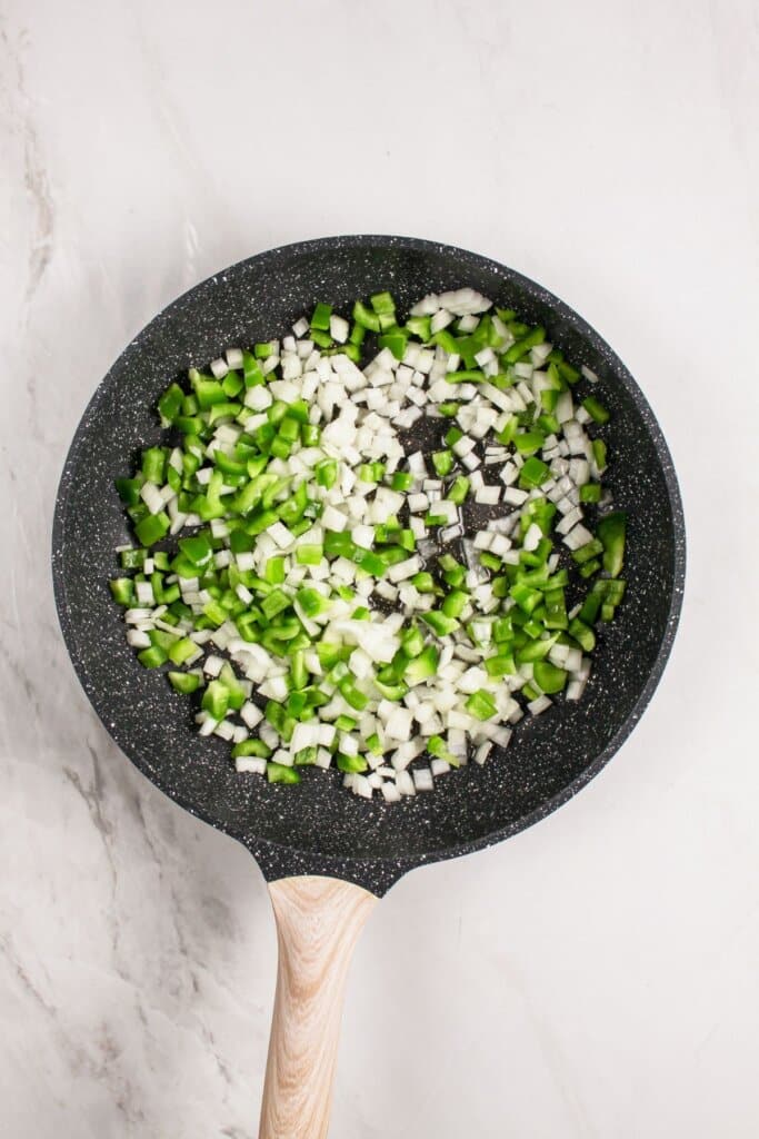 Peppers and onions being cooked in a skillet.