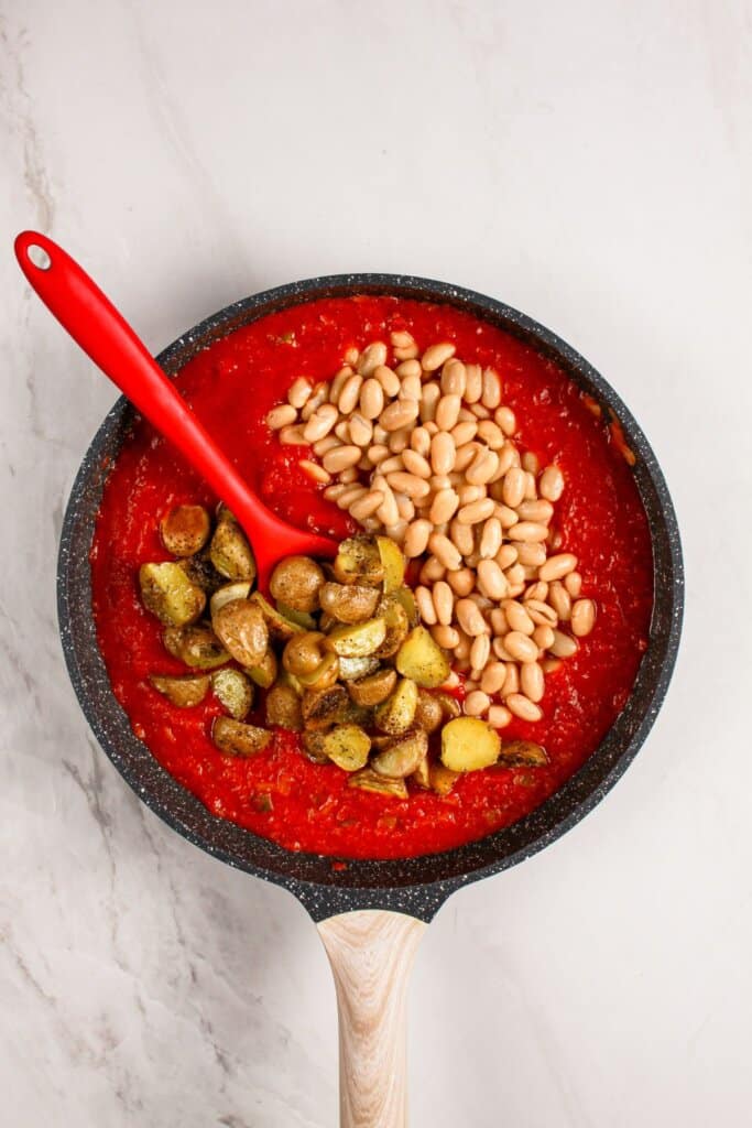 Beans being added to tomato sauce.