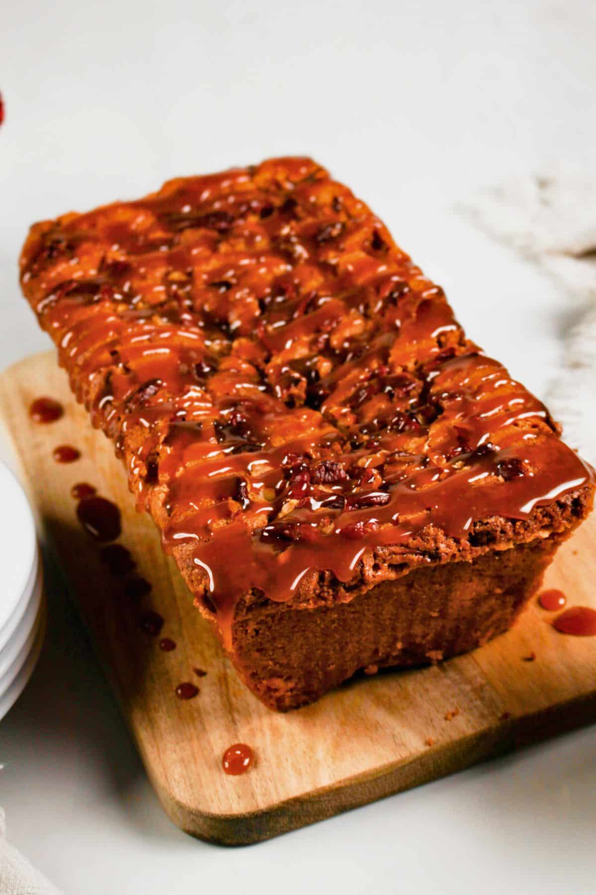 Loaf of pecan caramel dessert on a cutting board.