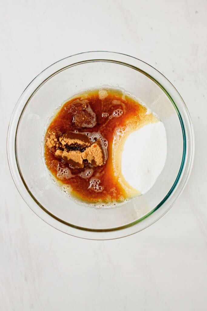 Brown sugar and butter being mixed together in a glass bowl.