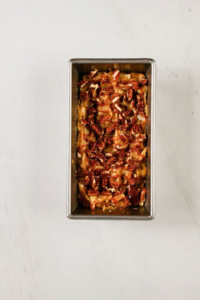 Batter and pecans in a loaf pan.