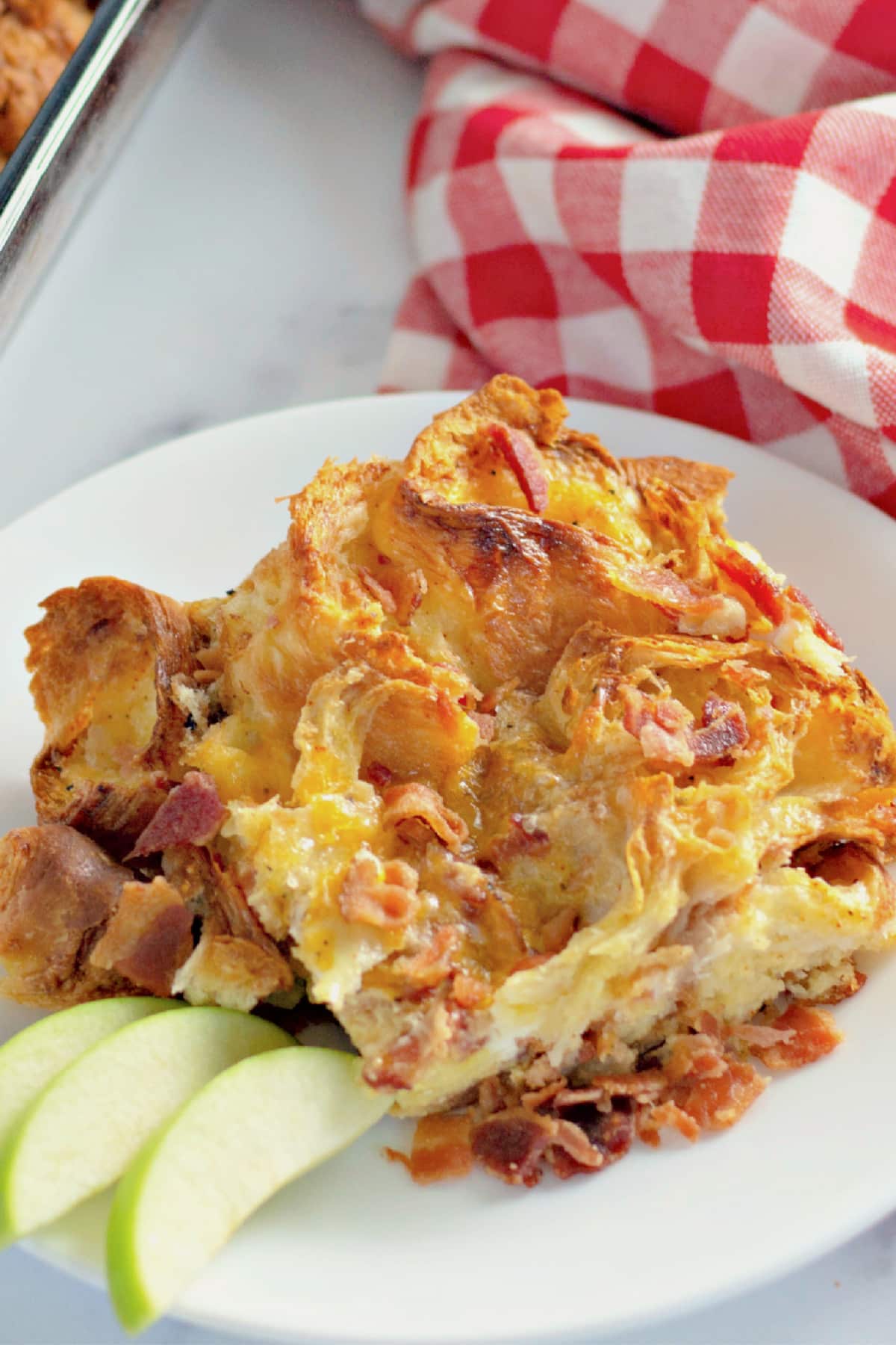 Serving of bacon croissant breakfast casserole on a plate.