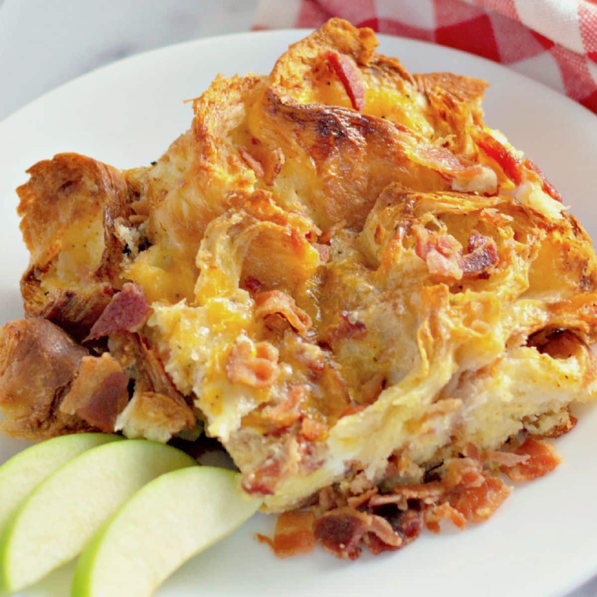 Serving of bacon croissant breakfast casserole on a plate.