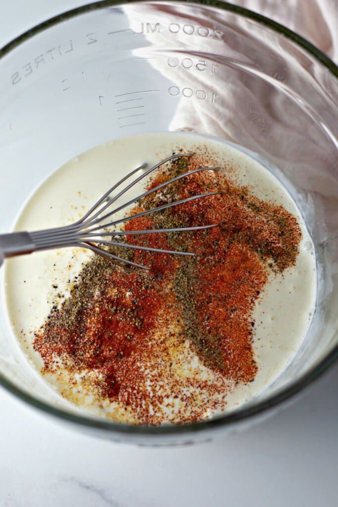 Custard being mixed in a glass bowl.