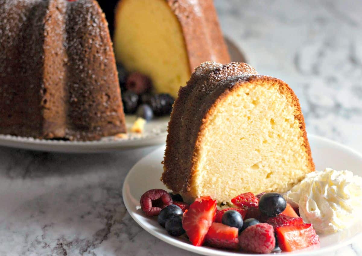 Slice of cream cheese pound cake with berries on a plate.