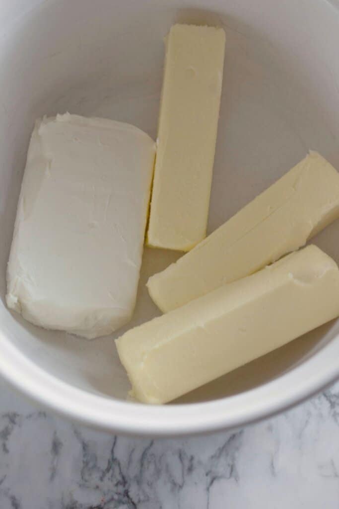 Butter and cream cheese being mixed in a bowl.
