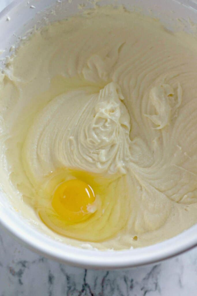 Eggs being added to batter in a mixing bowl.