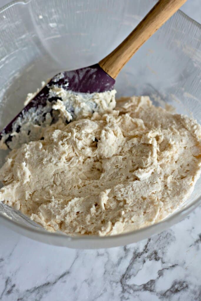 Dough being mixed in a glass mixing bowl.