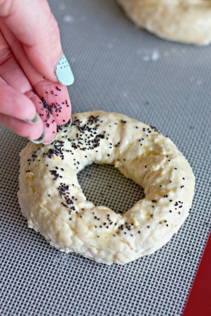 Seasonings being sprinkled on top of dough on a baking dish.