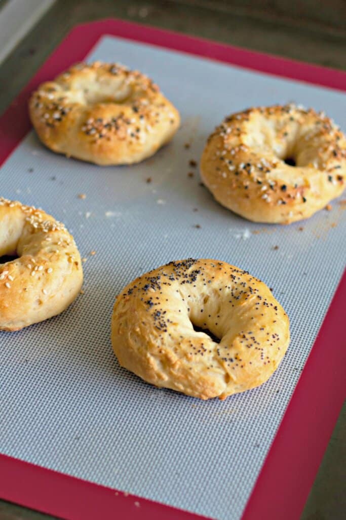 Cooked bagels cooling on a baking sheet.