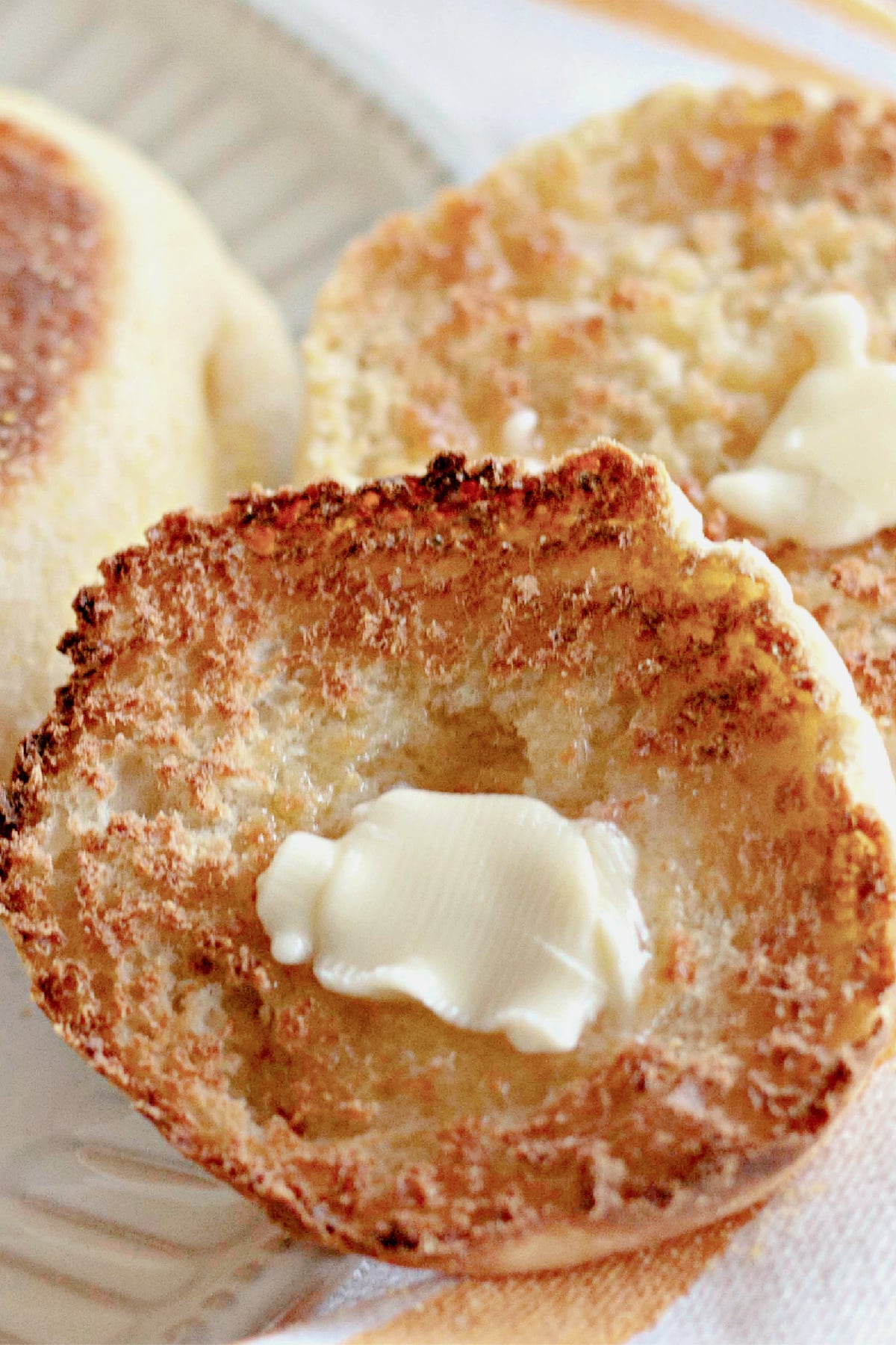 Butter being spread on an english muffin.