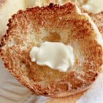 Butter being spread on an english muffins.