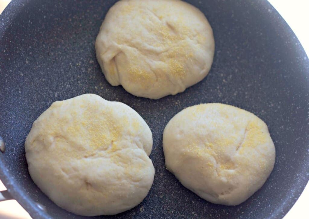 Dough being cooked in a dark skillet.