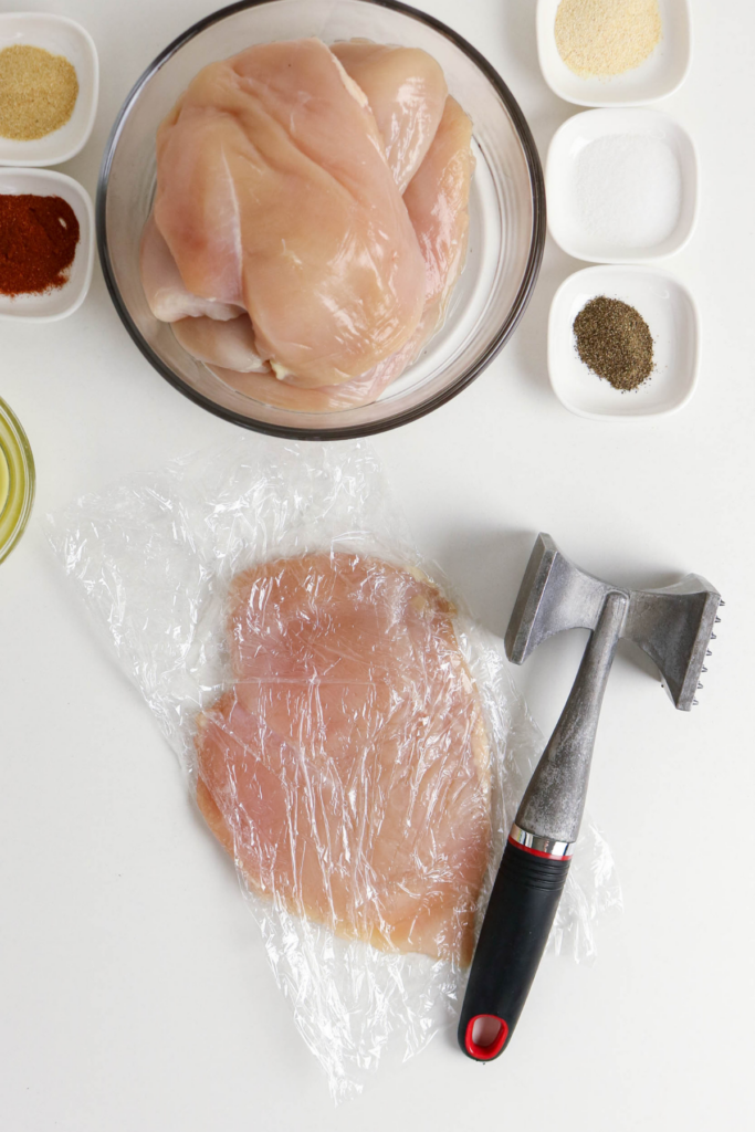 Pounding out the chicken breast to make it thin.
