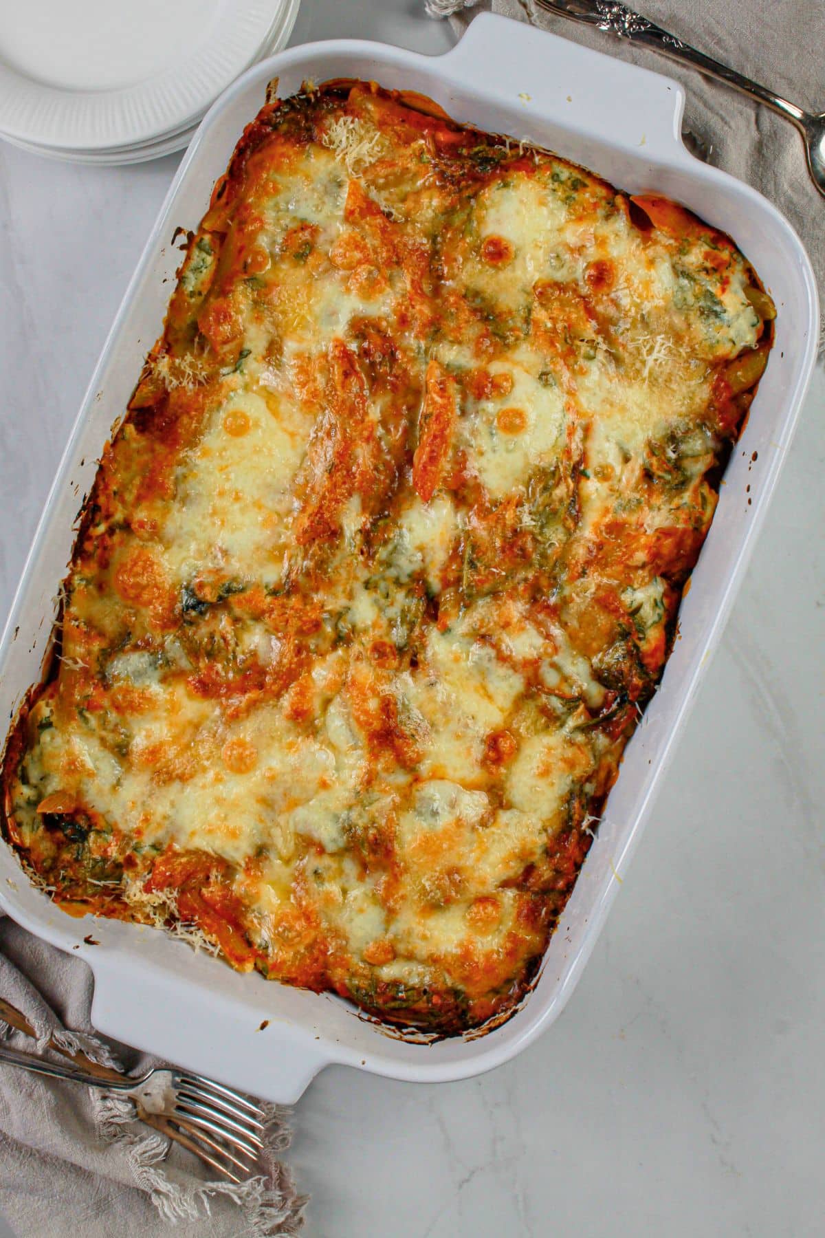 Baked ziti in a white casserole dish cooling on a counter.