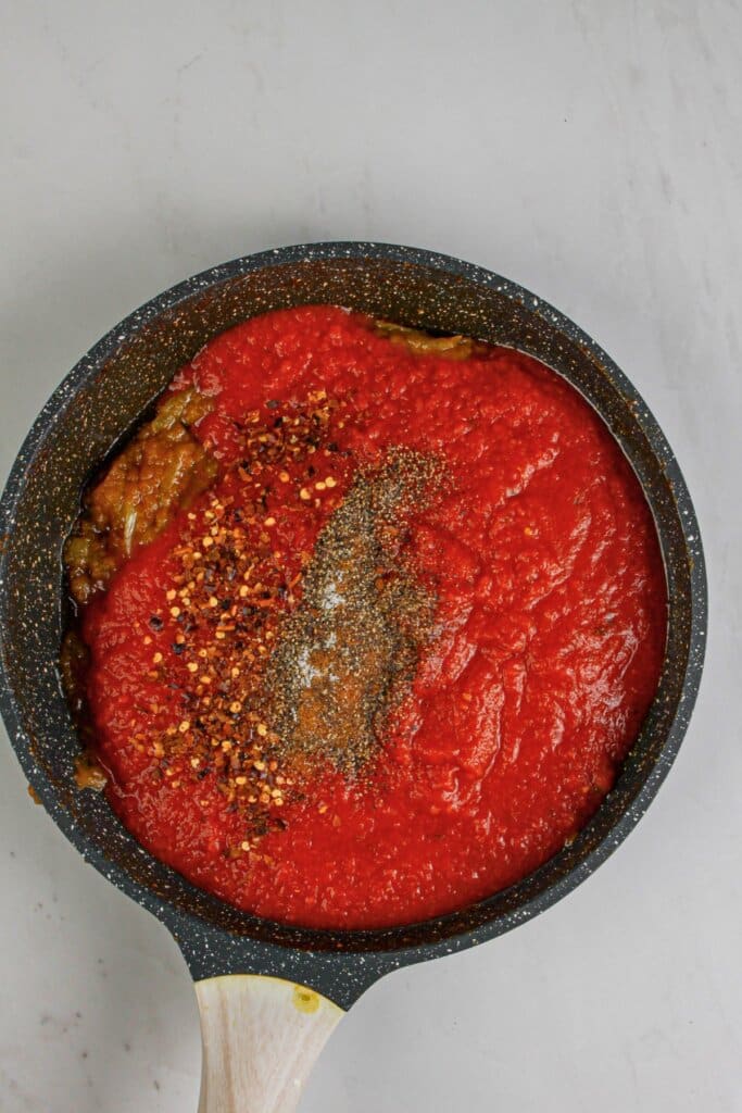 Sauce and seasoning being mixed in a skillet.