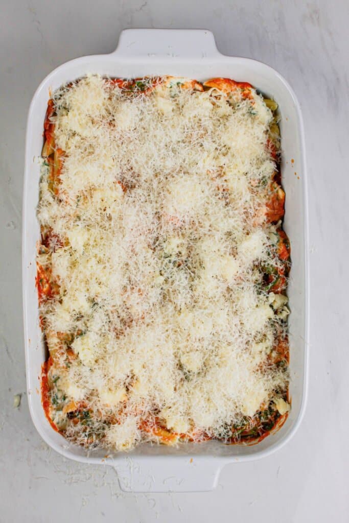 Cheese being sprinkled on top of a baking dish.