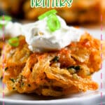 Onion fritter topped with sour cream on a small white plate.