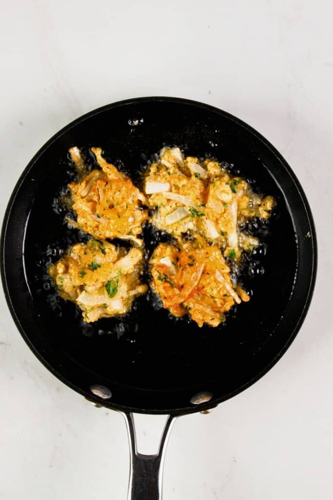 Batter being fried in oil in a skillet.
