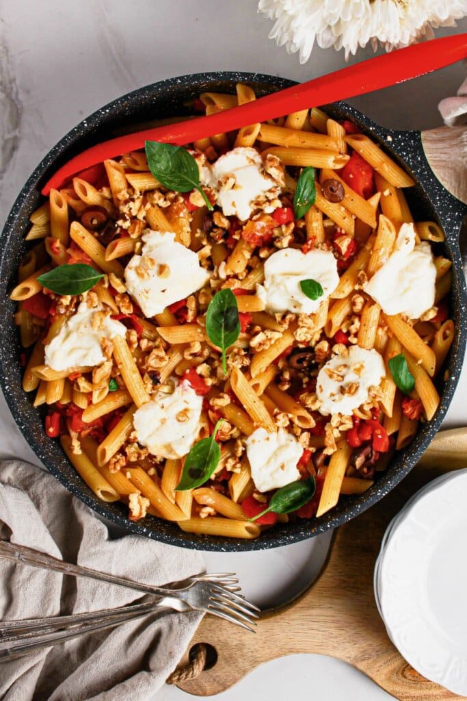 Skillet full of pasta topped with cheese.