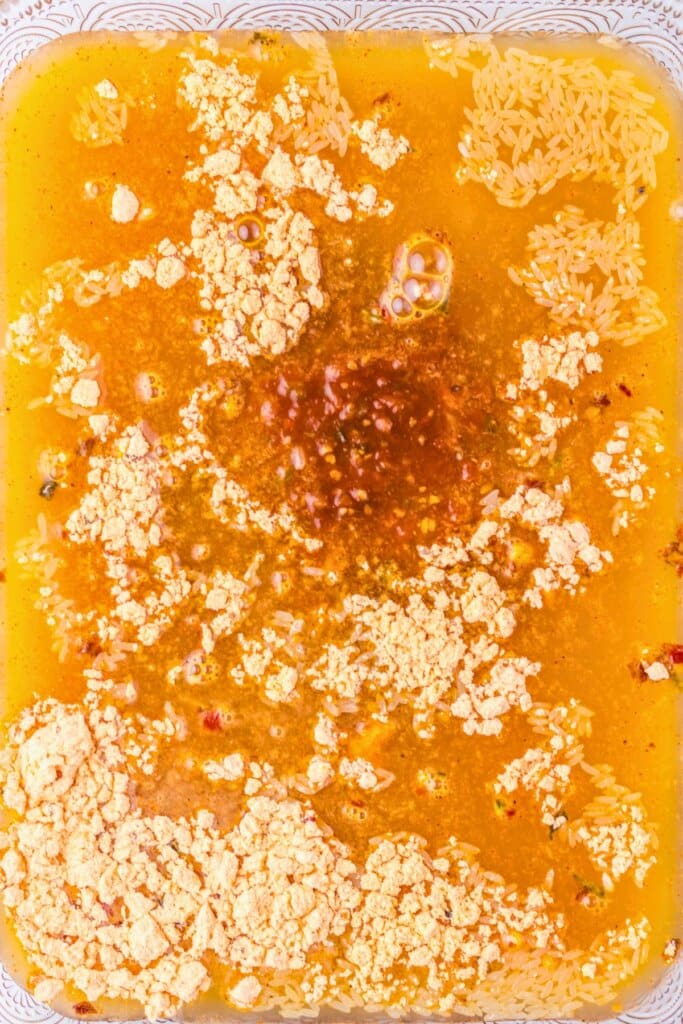 Seasoning and broth in a glass baking dish.