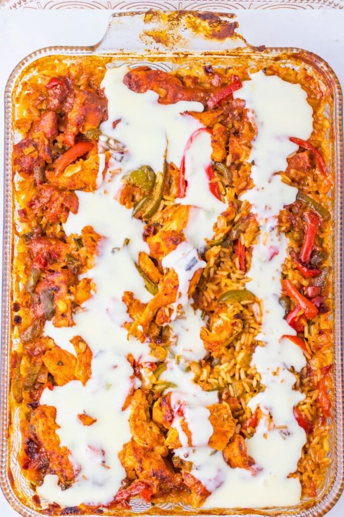 Cheese dip being poured on top of baked dish.