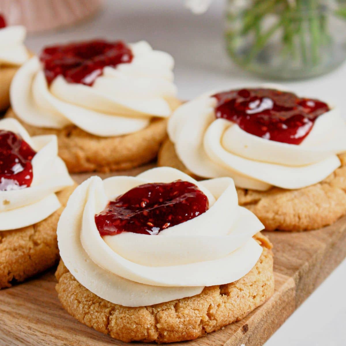 Raspberry cheesecake cookies on a wooden cutting board.