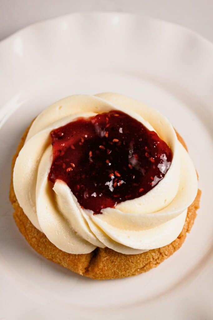 One raspberry cheesecake cookies on a small white plate.