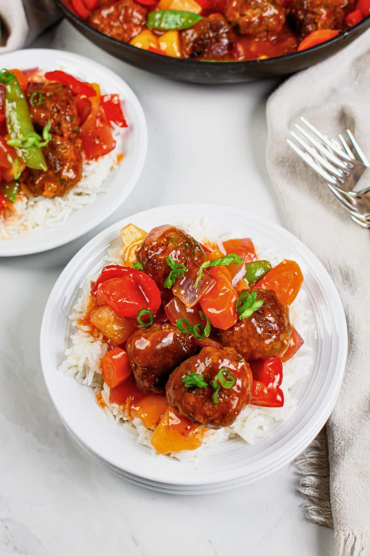 Small plate of rice topped with sweet and sour meatballs.