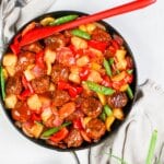 Skillet full of sweet and sour meatballs and veggies.