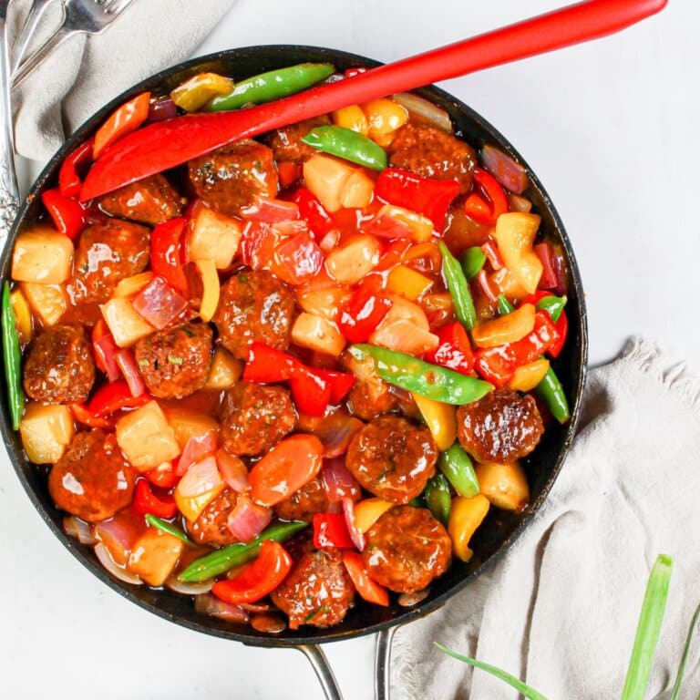 Skillet full of sweet and sour meatballs and veggies.